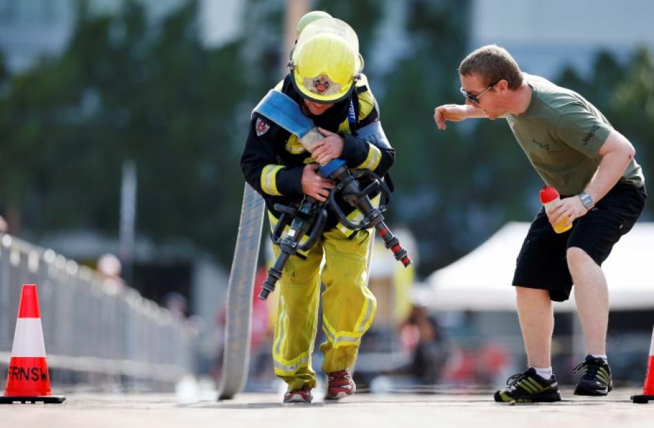 A teammate cheers on a firefighter from South Africa as he competes in the Toughest Firefighter...