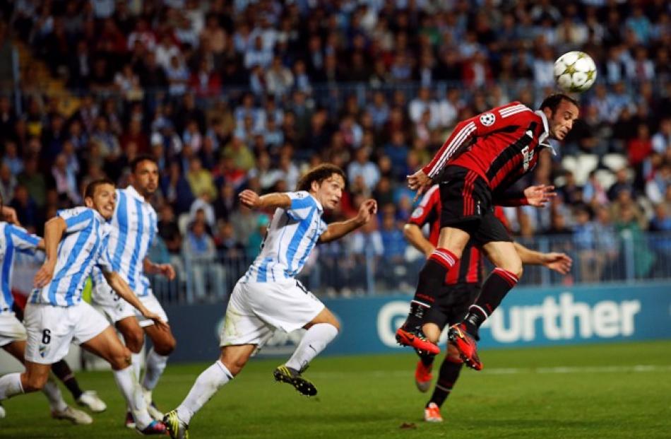 AC Milan's Giampaolo Pazzini (R) heads the ball next to Malaga's Manuel Iturra (C) during their...