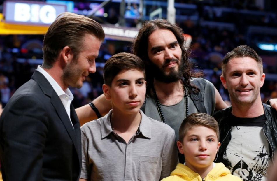 Footballer David Beckham (L) and actor Russell Brand (3rd L) pose for a photo with unidentified...