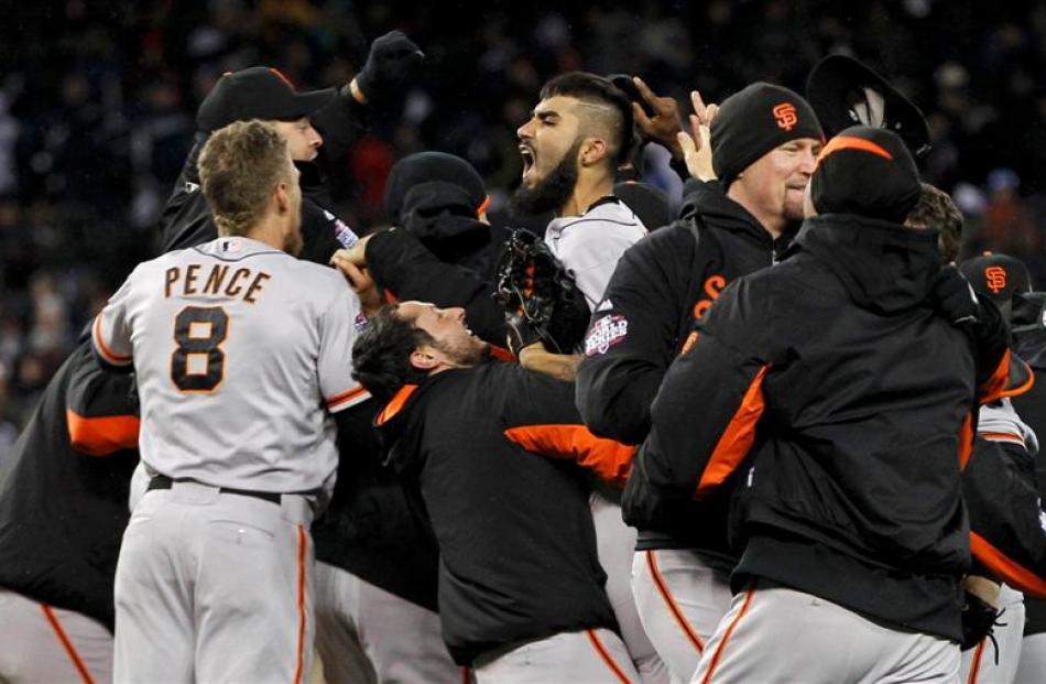 San Francisco Giants players surround relief pitcher Sergio Romo as they celebrate after winning...