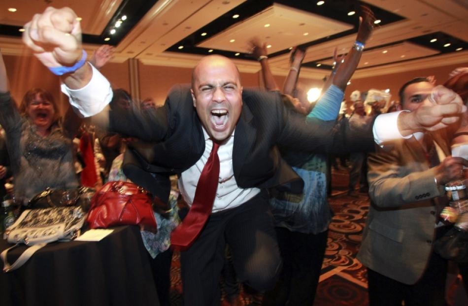 Ajay Narayan cheers as the race is called for U.S. President Barack Obama by a television network...