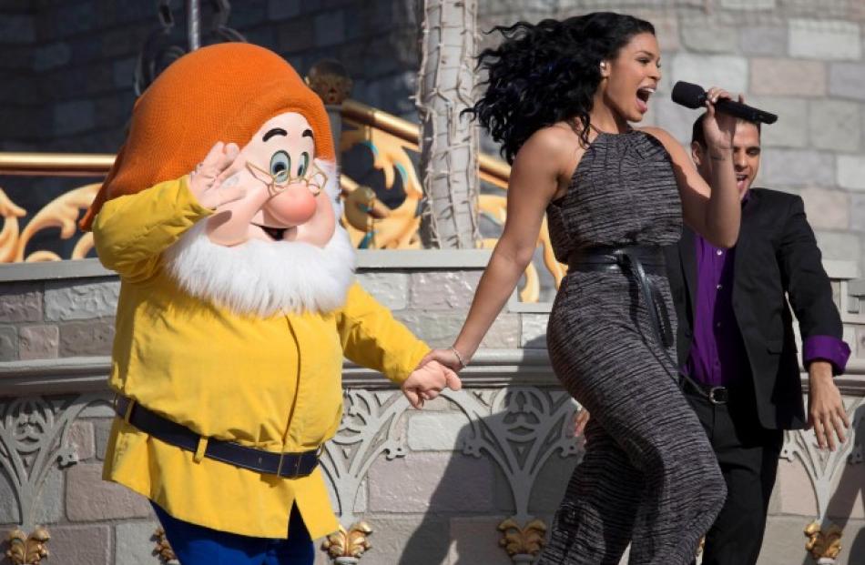 Singer Jordin Sparks performs with one of the Seven Dwarfs during the grand opening ceremony for...