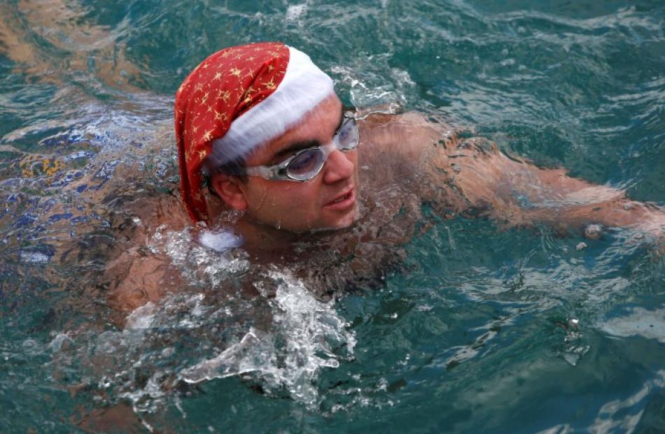 A man in a Santa hat takes part in a charity swim at the marina of the Grand Hotel Excelsior in...