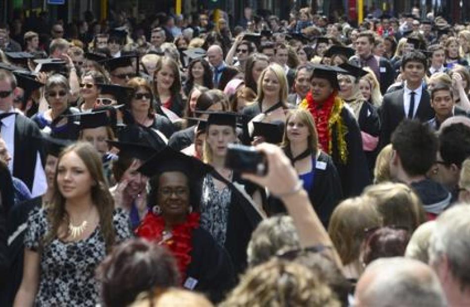 Relatives and other well-wishers watch graduands head along George St, Dunedin, before their...