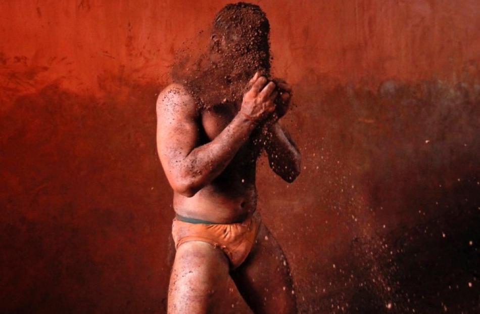 A wrestler rubs his hands with mud to prevent slipping due to sweat during a traditional mud...