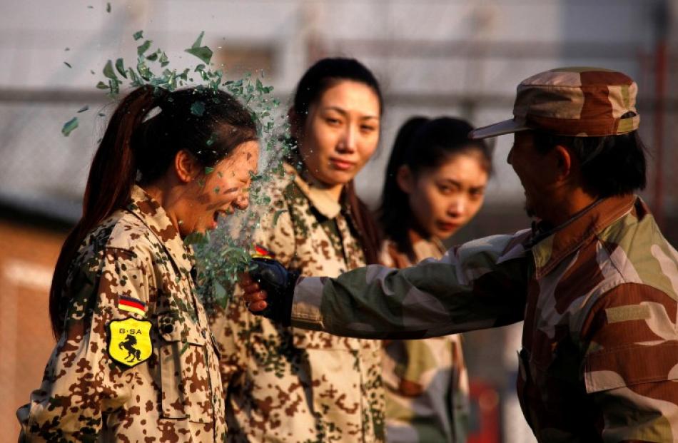 An instructor from the Tianjiao Special Guard/Security Consultant Ltd. Co smashes a bottle over a...