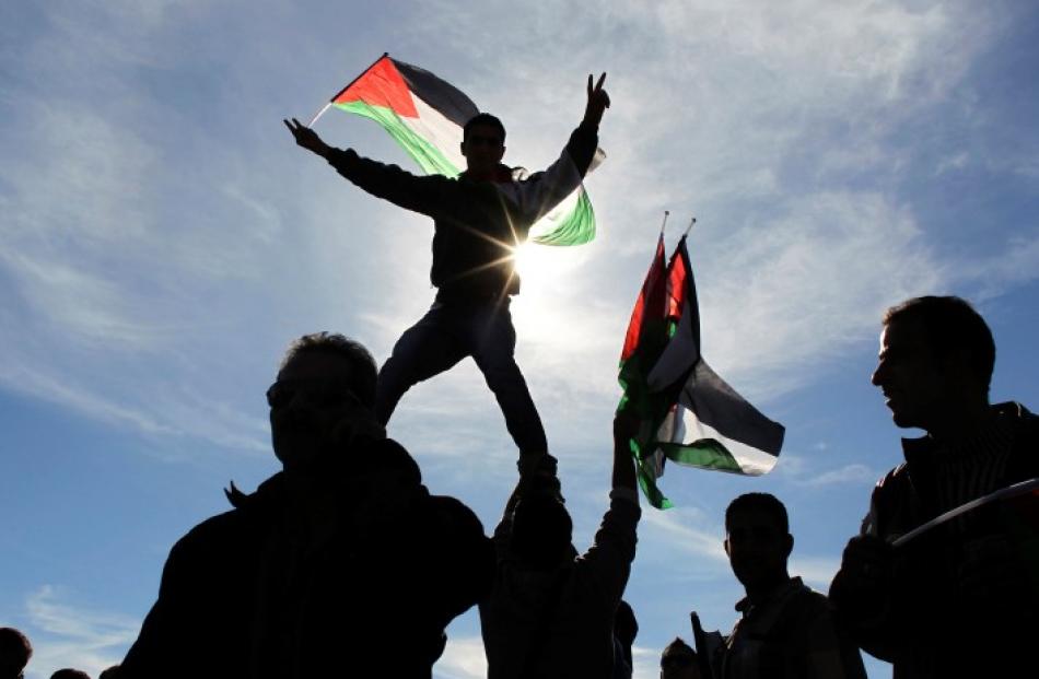 Palestinians wave flags during a rally marking the UN General Assembly's upgrading of the...