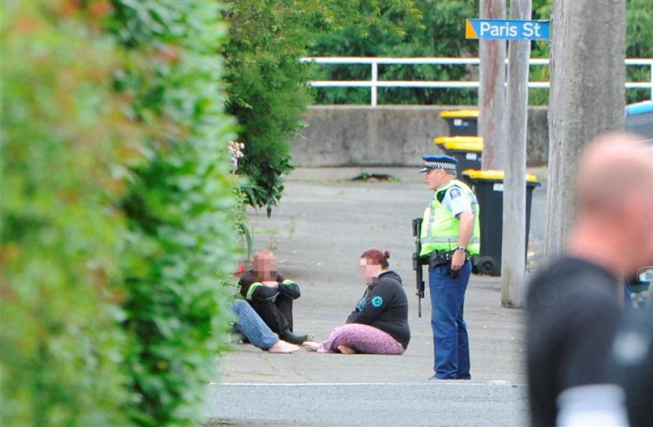 A woman and two men wait after being evacuated from a house in Northeast Valley yesterday, after...