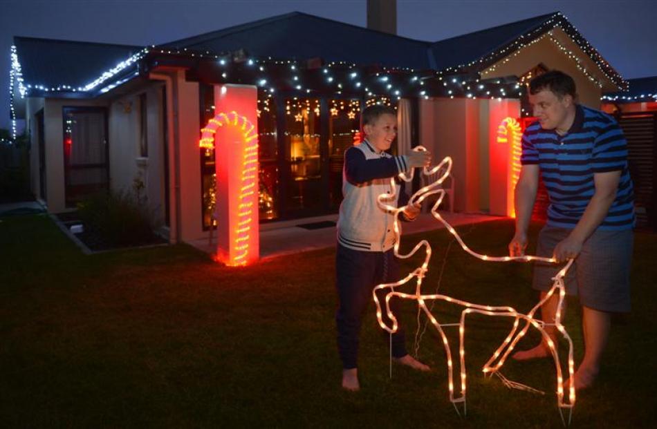 Mosgiel resident Jason Merrett and his son, Blake, install Christmas decorations outside their...
