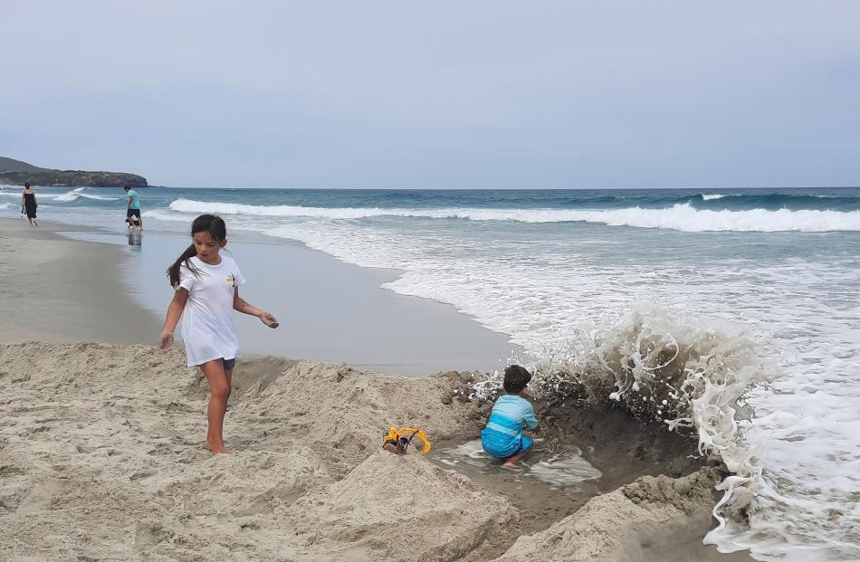 Erin (8) and Jonathan (4) Loo unsuccessfully protecting their sand castle at Middle Beach on...
