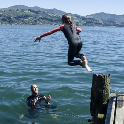 Elouise Miller jumps down to her father Roger Miller off the Macandrew Bay jetty on Boxing Day....