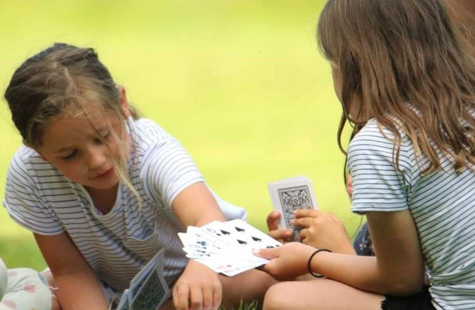 Twins Sadie and Billie Bradfield (7) play cards at a family picnic with their cousins at Tawanui...