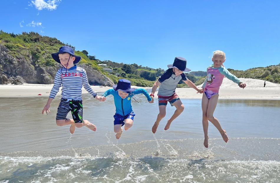 Edward (7) and Albert (5) Craw jump waves at Tomahawk Beach, accompanied by Max and Evie Bisset ...