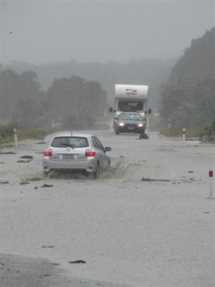 Motorists cautiously negotiate a flooded section of State Highway 6 about 2km north of Makarora...