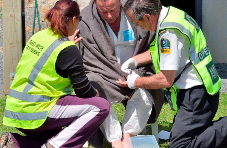 Emergency service staff attend one of the four men rescued from the sea off Taieri Mouth...