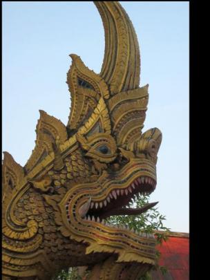 A fierce-looking creature gazes out from a Thai temple.