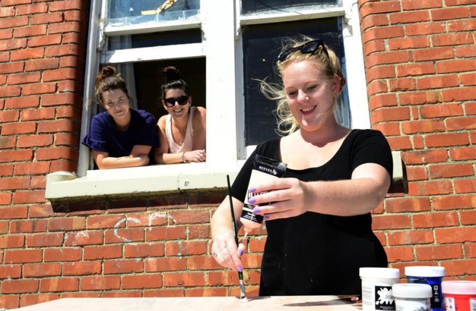 Becki Mudford (21), of Auckland, gives a table a fresh lick of paint, while (from left) Janelle...