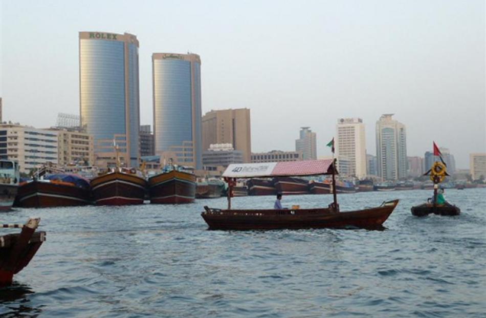 A water taxi passes docked dhows while crossing The Creek. Photo by Neville Peat.