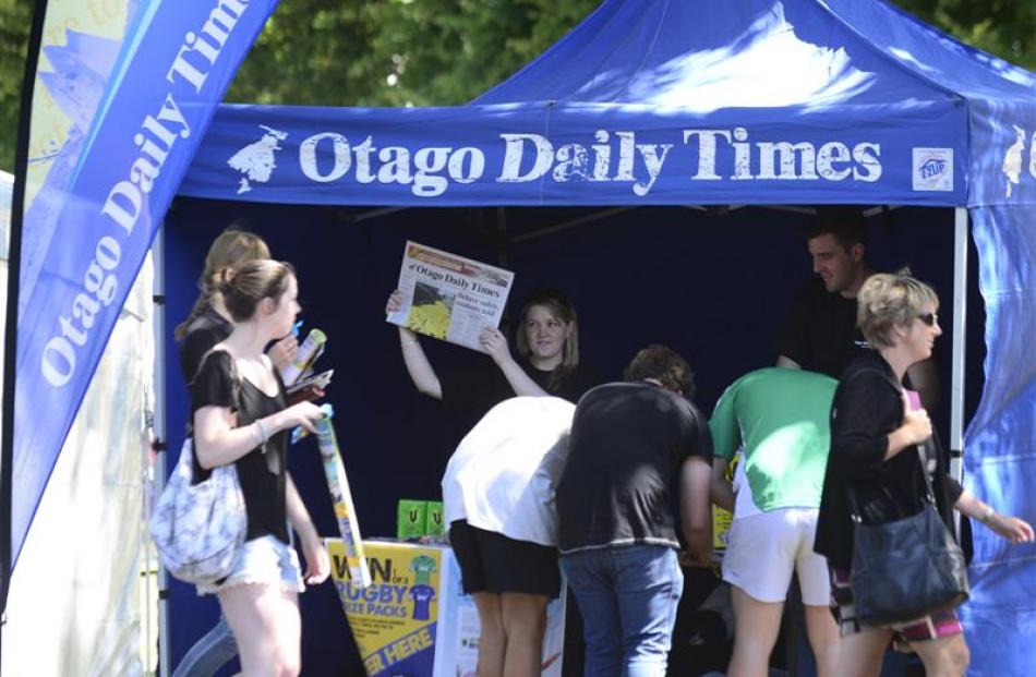 Jess Peck, of the Otago Daily Times, holds up a newspaper at one of the many stalls at tent city....