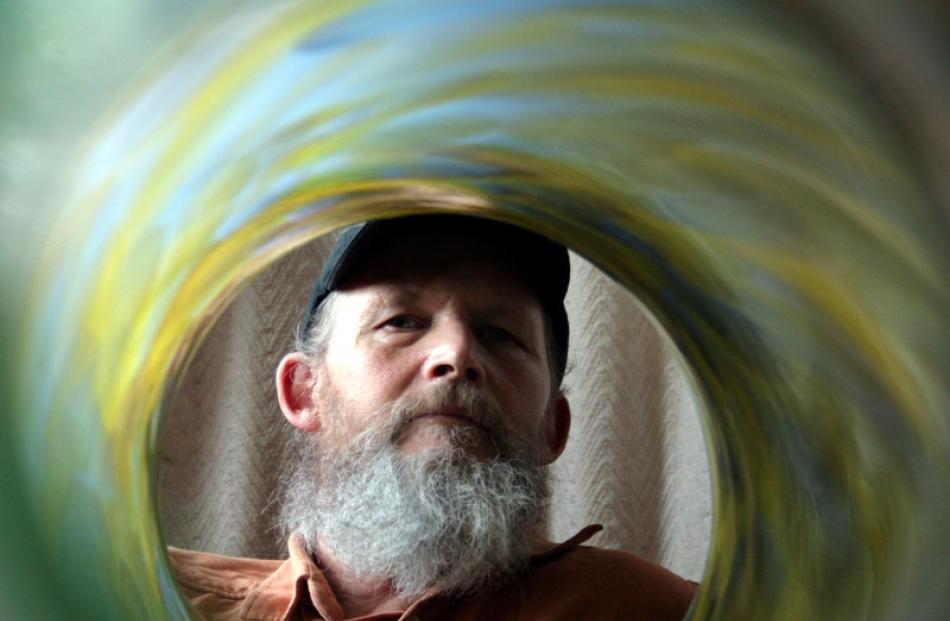 Otago Stained Glass master glass painter Peter Mackenzie  looks through a tube of glass at his...