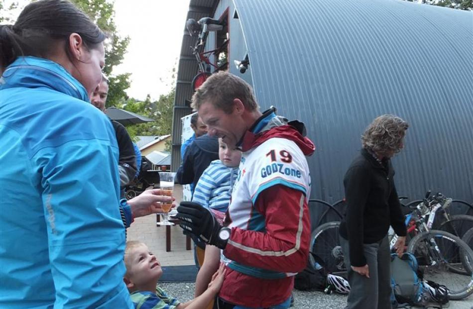 Mike Kelly is greeted by a glass of bubbly and his two boys at the finish line yesterday. Photos...