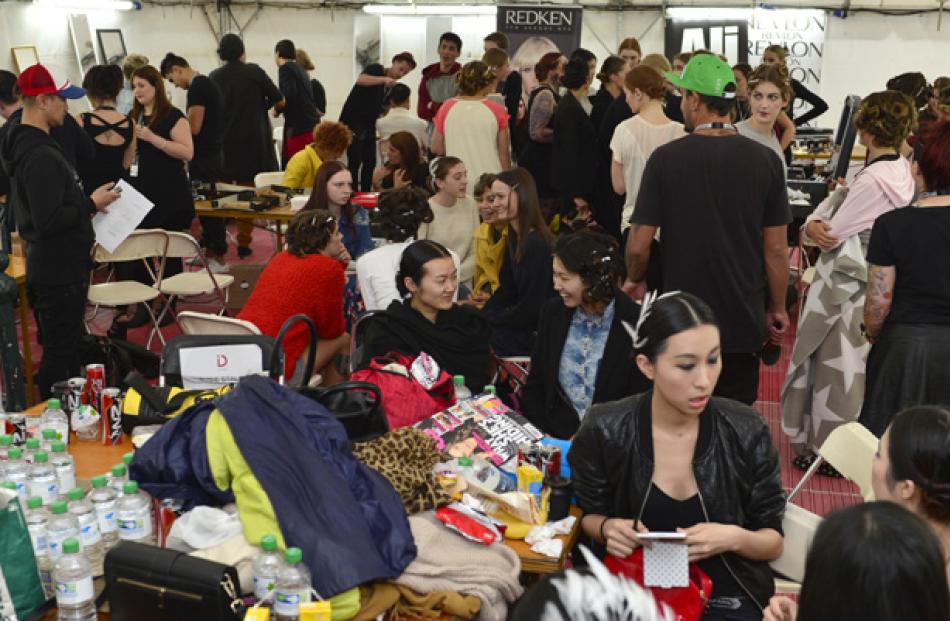Models, designers, make-up artists and hair stylists prepare backstage for the show.