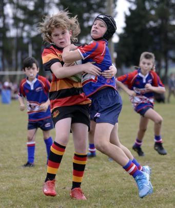 Eli Olsen (11, right), of the Harbour Hawks, tries to barge through the tackle of Joey Annison ...