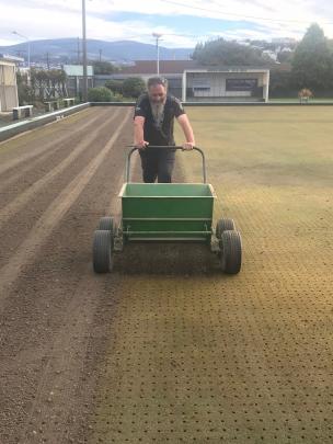 Following the aeration process, Wally Shaw spreads fine soil over the green.
