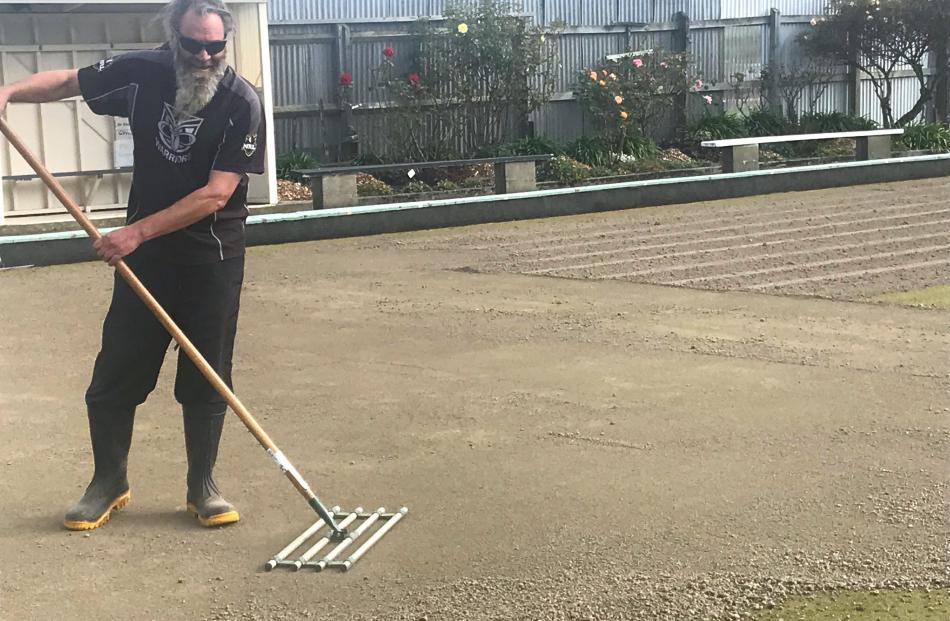 St Kilda Bowling Club member Wally Shaw uses a special rake to smooth the soil. 