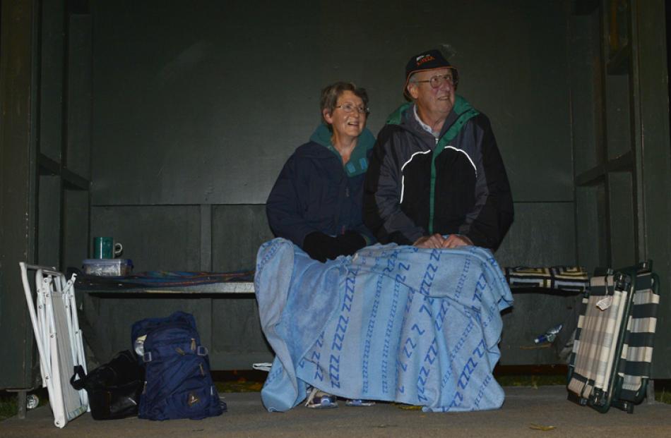 A couple enjoy the music from a bus shelter opposite the stadium.