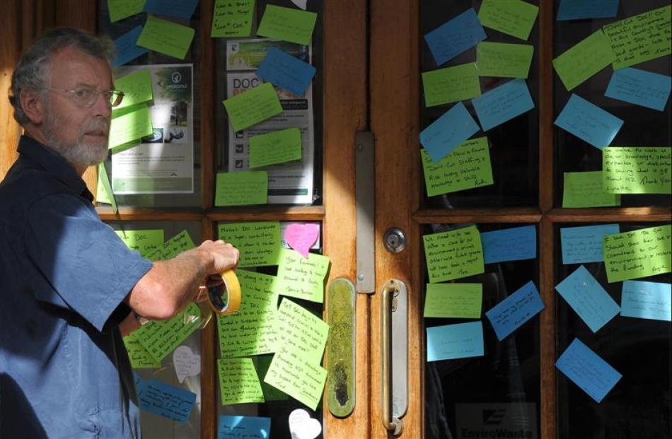 Forest and Bird Dunedin spokesman Mark Hanger sticks up a message of support for Department of...