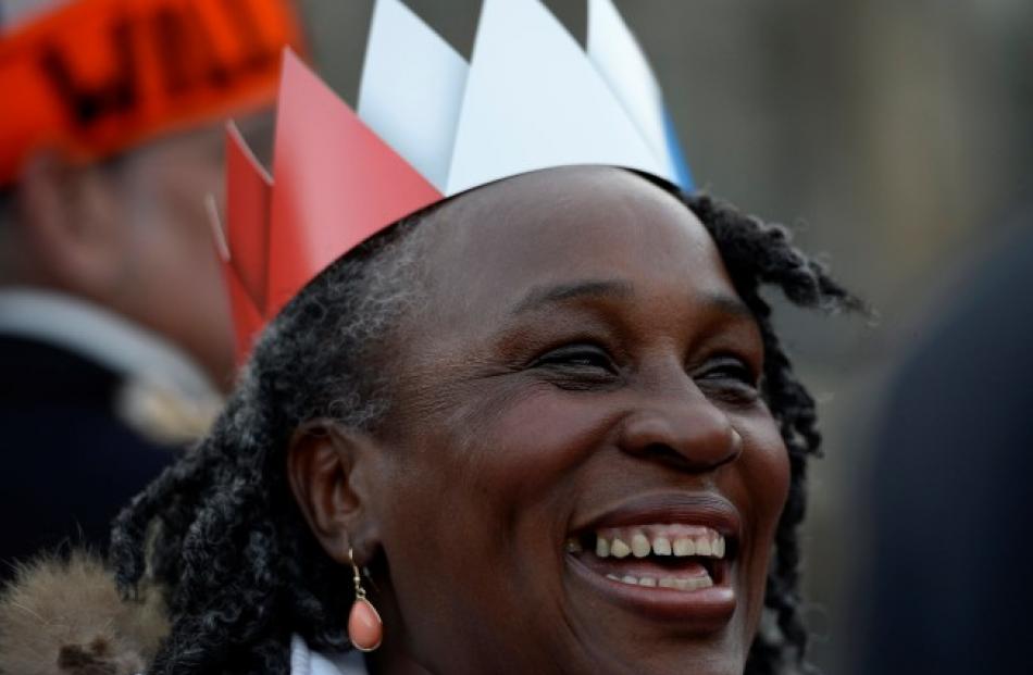 A woman wearing a paper crown laughs in front of the Royal Palace in Amsterdam. REUTERS/Dylan...