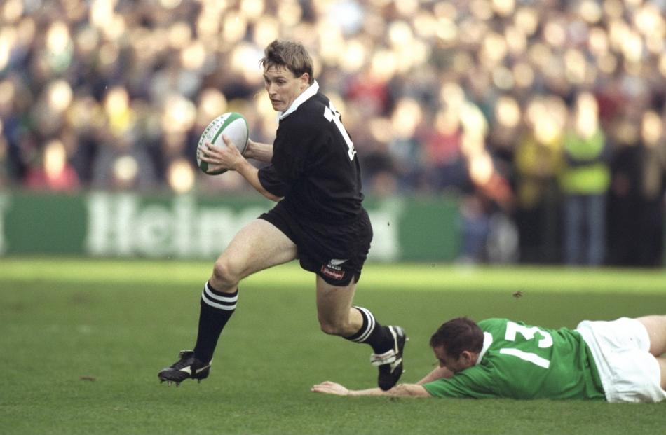 1997. All Blacks first five Andrew Mehrtens evades the tackle of Rob Henderson during the test at...