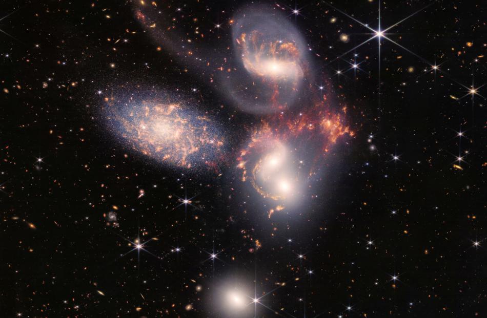 A group of five galaxies that appear close to each other in the sky: two in the middle, one...