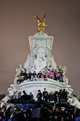 Crowds gather on the Queen Victoria Memorial in front of Buckingham Palace after the Queen’s...