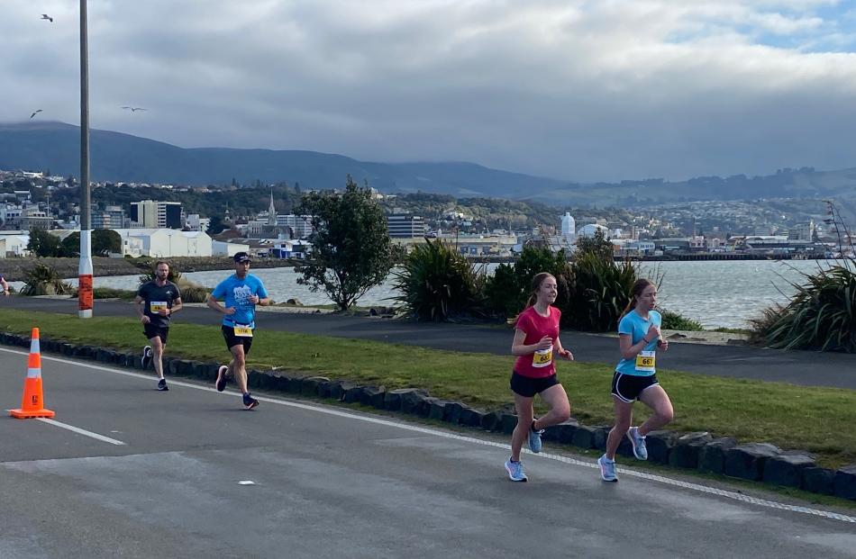 Runners Alex Robinson (front left, 683) and Rebekah Robinson (667) stride along Portsmouth Dr...
