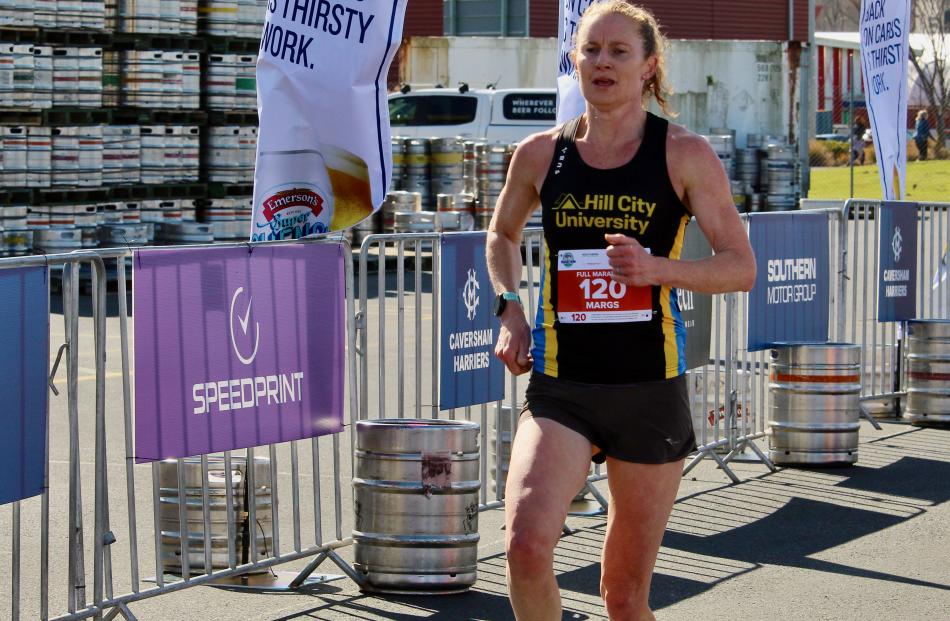 Margie Campbell, of Dunedin, celebrates reaching the finish line to win the women’s category of...