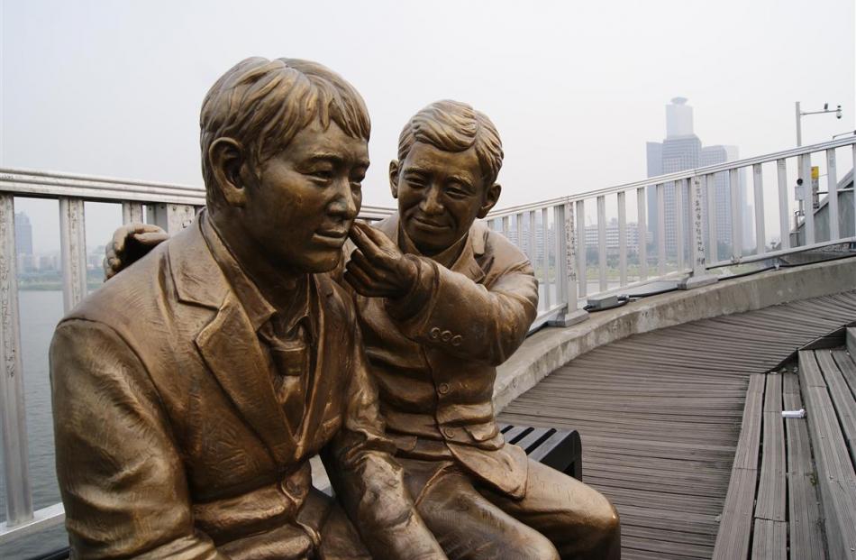 Bronze figures - an older man pinches the cheek of the younger.