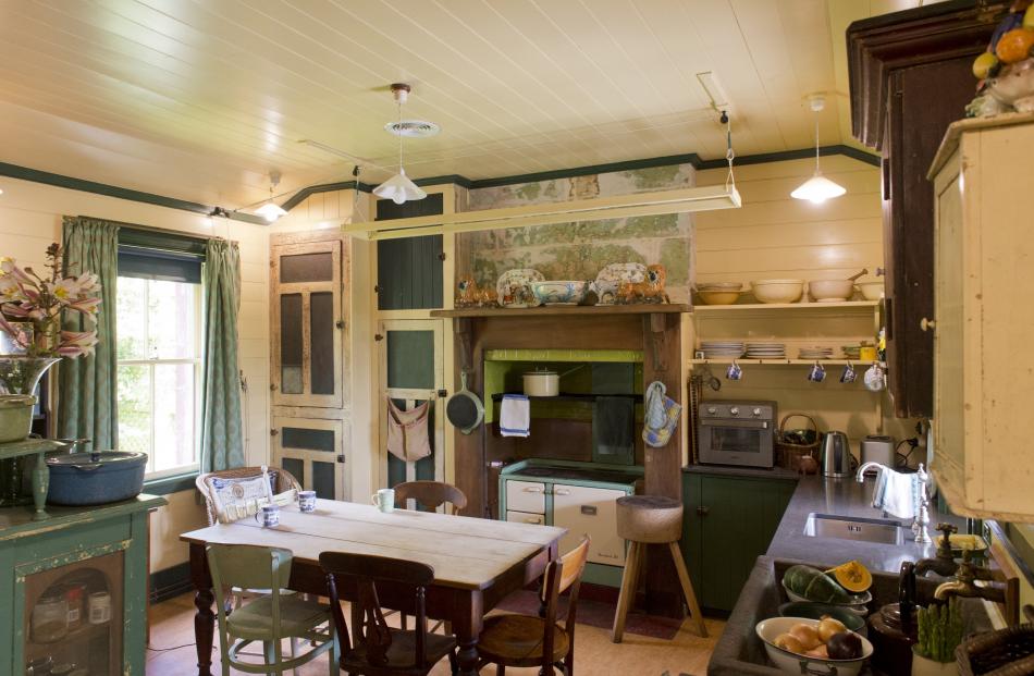 The kitchen cupboard doors are original. A small bench-top stove is used for baking, but the coal...