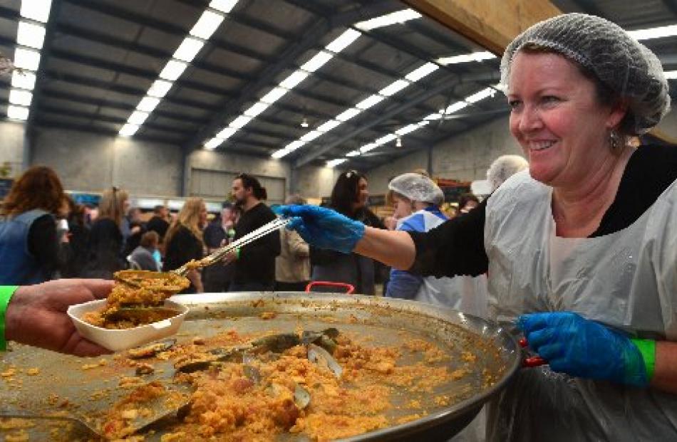 Kathy Scott, of Dunedin, serves paella to festival-goers.