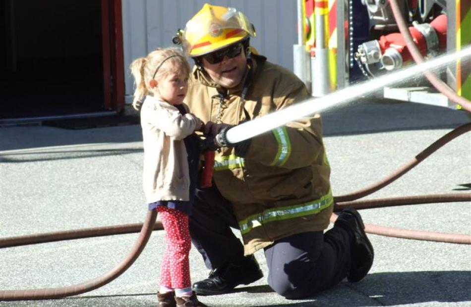 Penny Aggerholm (4), from Wakatipu Kindergarten, is helped by senior volunteer firefighter...