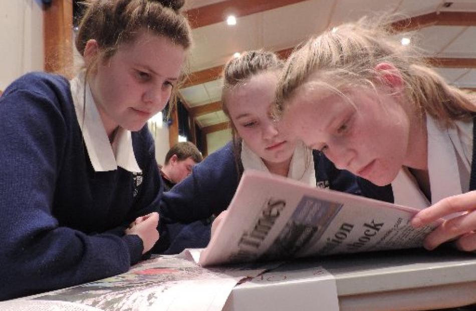 Poring over the Otago Daily Times  in search for an answer are the Opihi College team of (from...