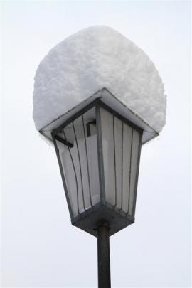 Snow on a street lamp.