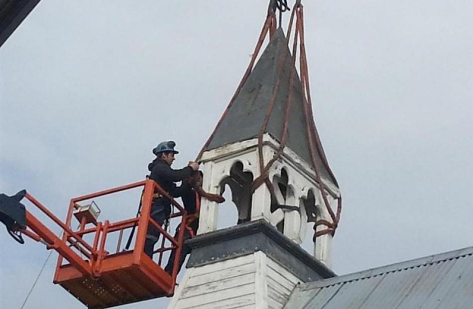 Builder Shaun Hunter attaches ropes to the bell tower before it was removed in  July, using a...