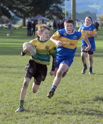 Green Island player Mason Bond (11) runs to the try line with Charlie Craig (12), of Taieri,...