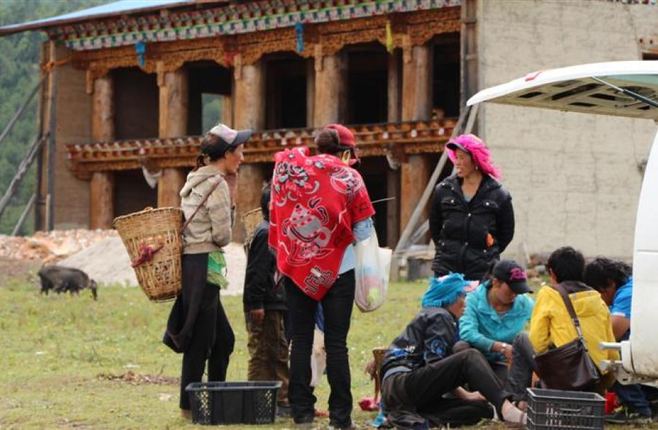 Tibetan mushroom-gatherers display their wares in front of an enormous partially built home on...