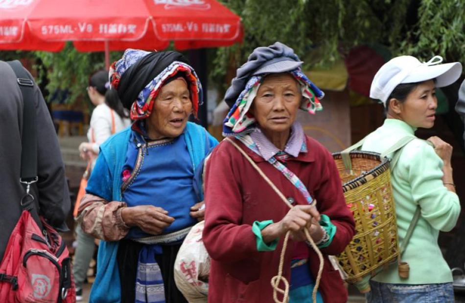 wo senior women from the Bai ethnic group wear traditional headgear to the morning market in...