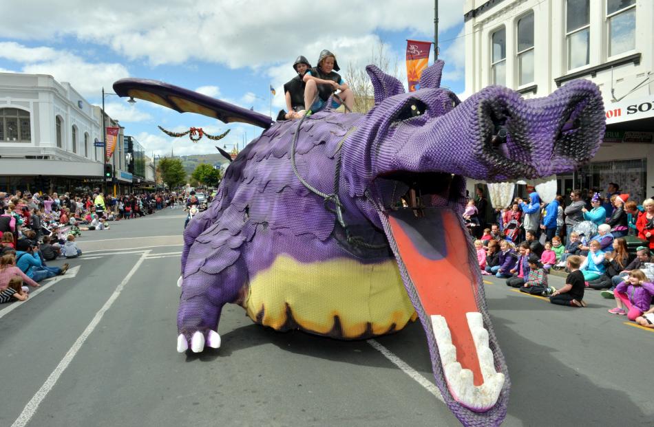 A purple dragon float roars along the street.