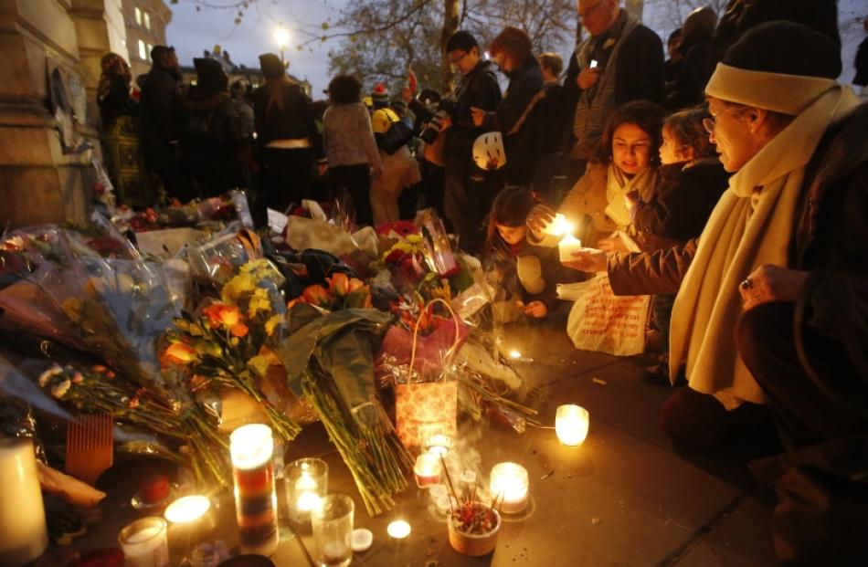 A family light candles among tributes and flowers for South Africa's former president Nelson...