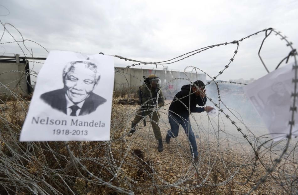 A placard depicting former South African President Nelson Mandela hangs on a barbed wire during...
